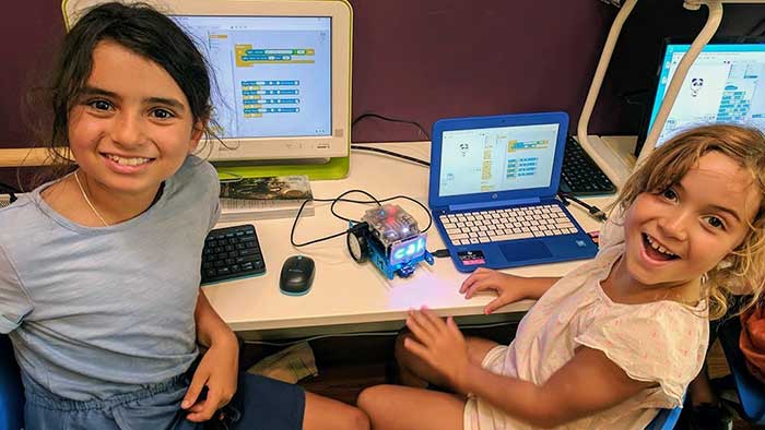 Girls use text-based code to make a robot move in our coding classes for kids