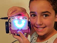 Girl shows off the LEDs she coded on a robot in our coding classes for kids