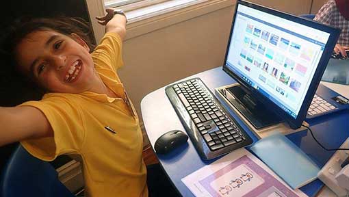 Girl smiles as she spreads her arms wide at one of her first kids coding classes